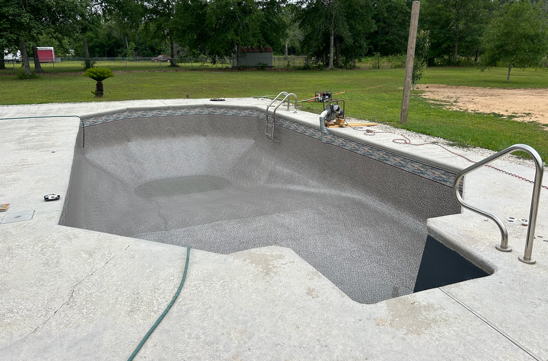 A large swimming pool in the backyard of a house with a wooden fence.
