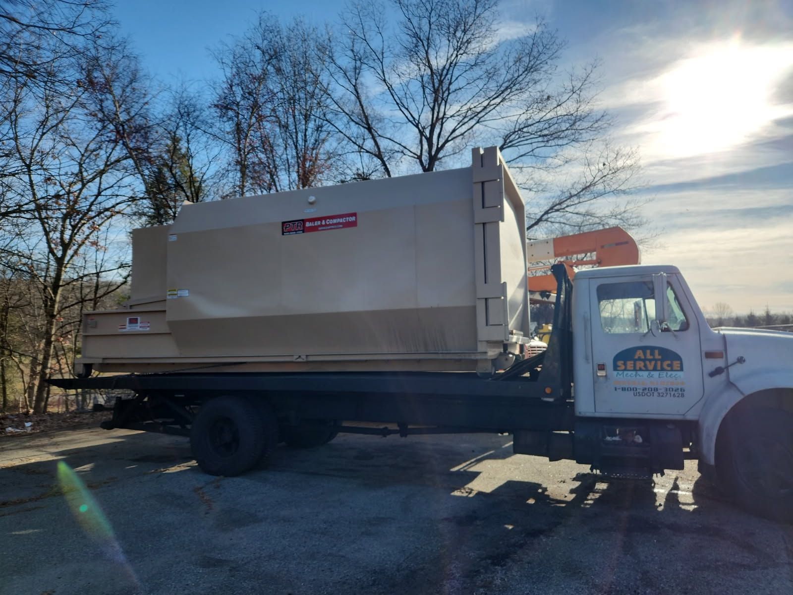 Tan dumpster on a white truck bed with