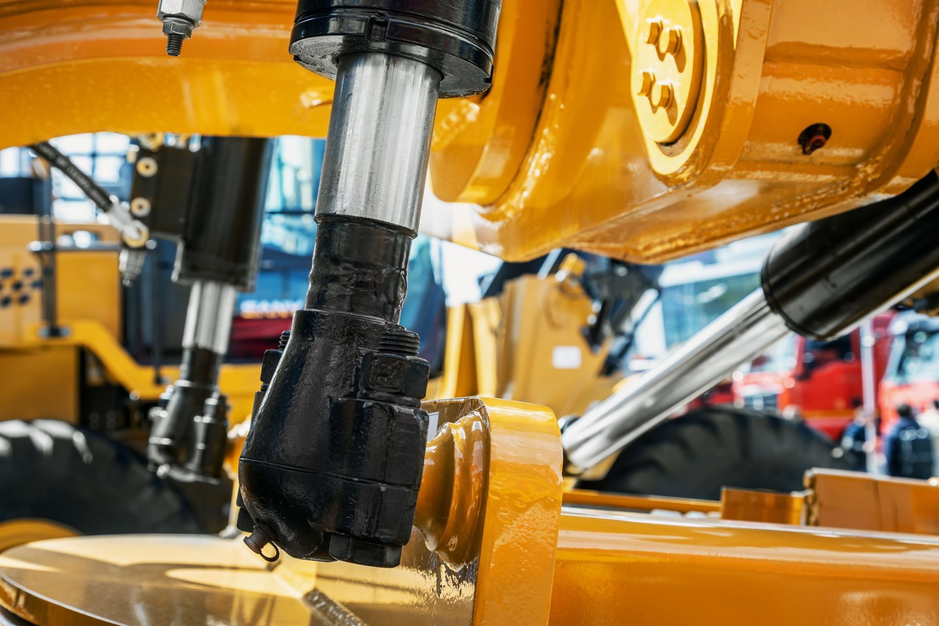 Yellow and black machinery hydraulic component with silver cylinder.