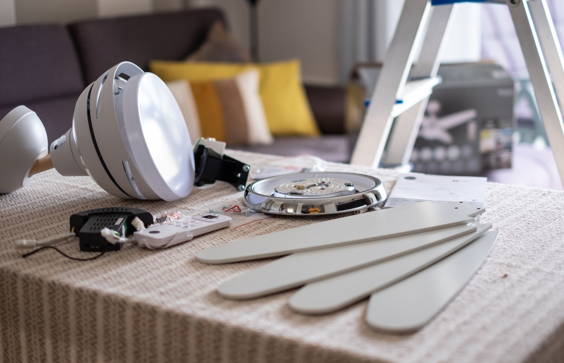 White headphones and a remote on a bed beside a tablet and white smartphone cases