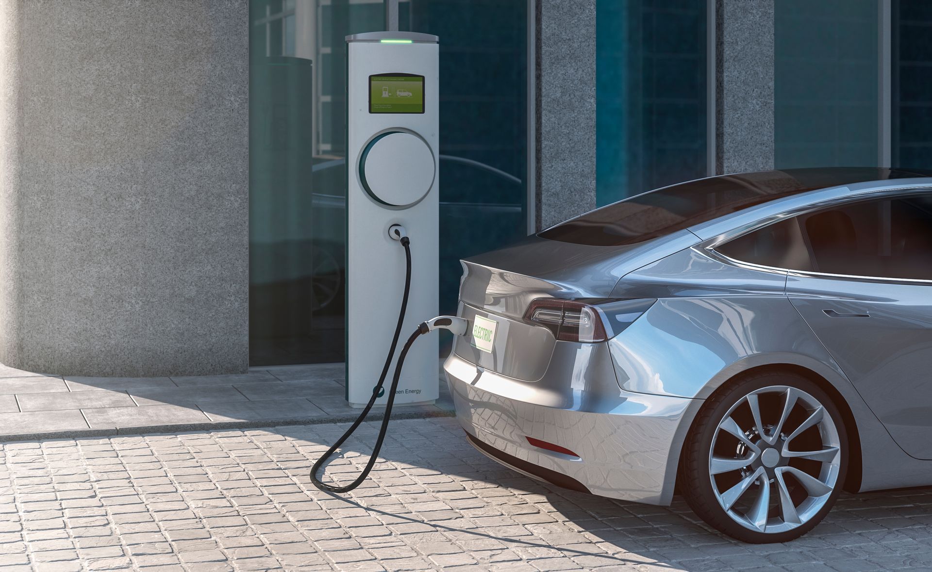 Silver car plugged into an EV charging station outside a modern building