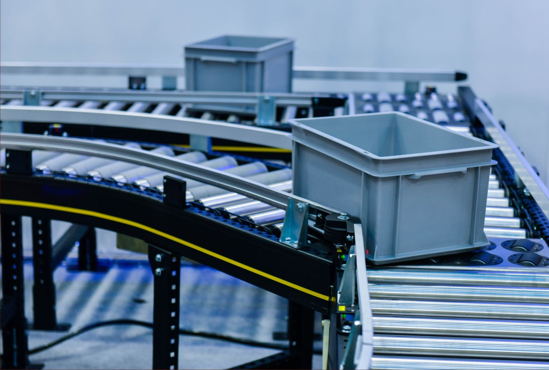 Miniature conveyor system with gray bins moving along black and yellow tracks