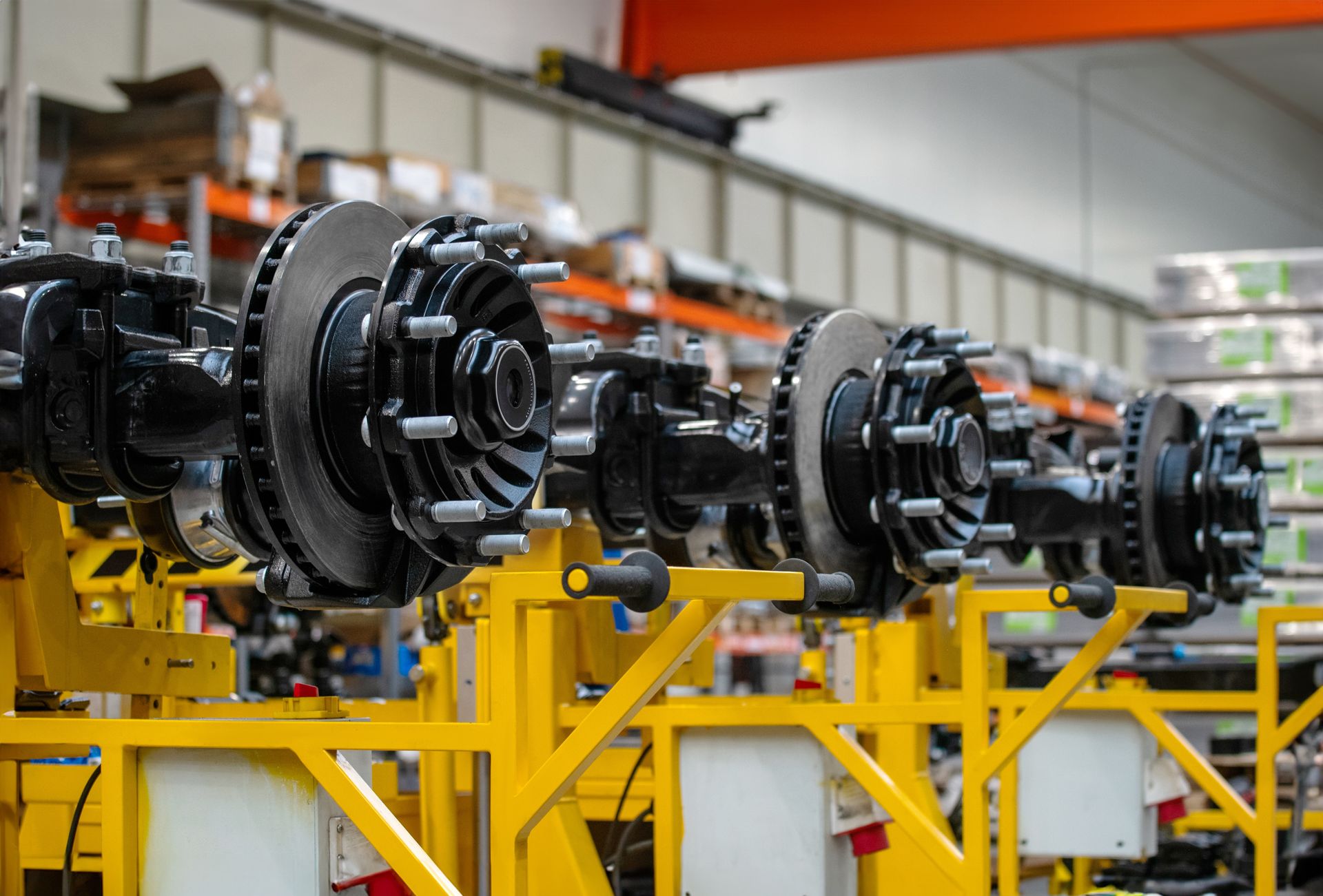 Assembly line with black mechanical parts mounted on yellow industrial racks in a factory