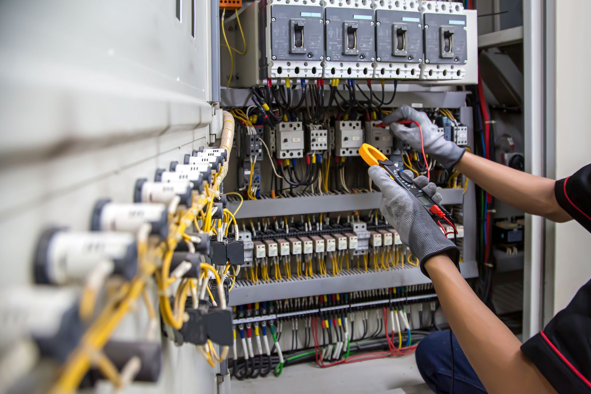 Technician wiring an electrical control panel with yellow and black cables