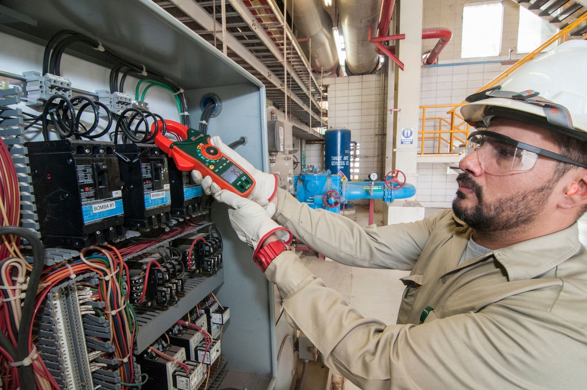Technician inspecting electrical panel with a multimeter in an industrial facility