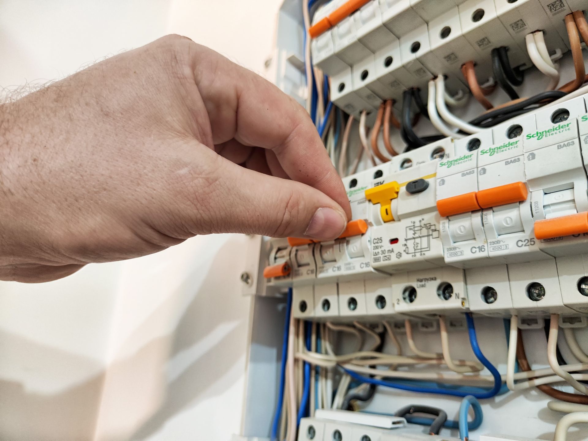 Hand adjusting a breaker switch in an electrical panel with exposed wiring