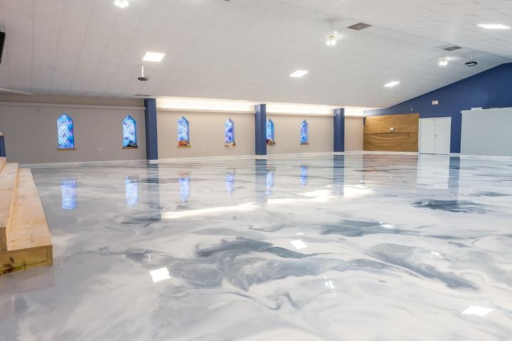 Empty indoor hall with glossy white floor, arched windows, and blue walls