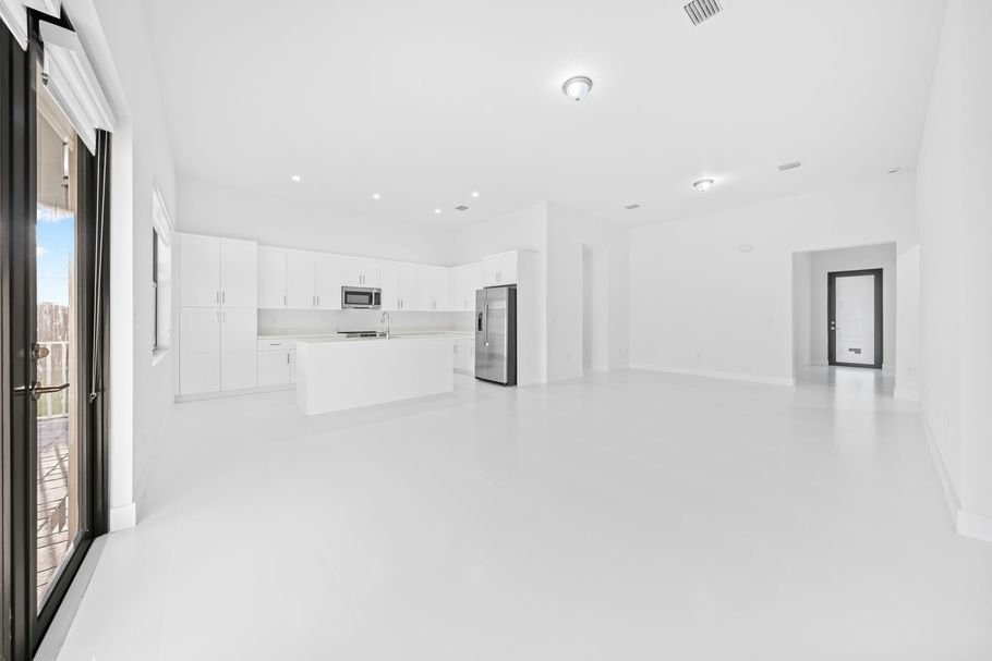 Bright empty white modern kitchen and living space with large windows and glossy floors