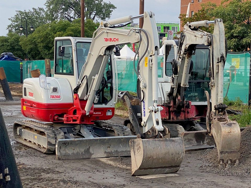 Deux excavatrices sont garées l'une à côté de l'autre sur un chemin de terre.