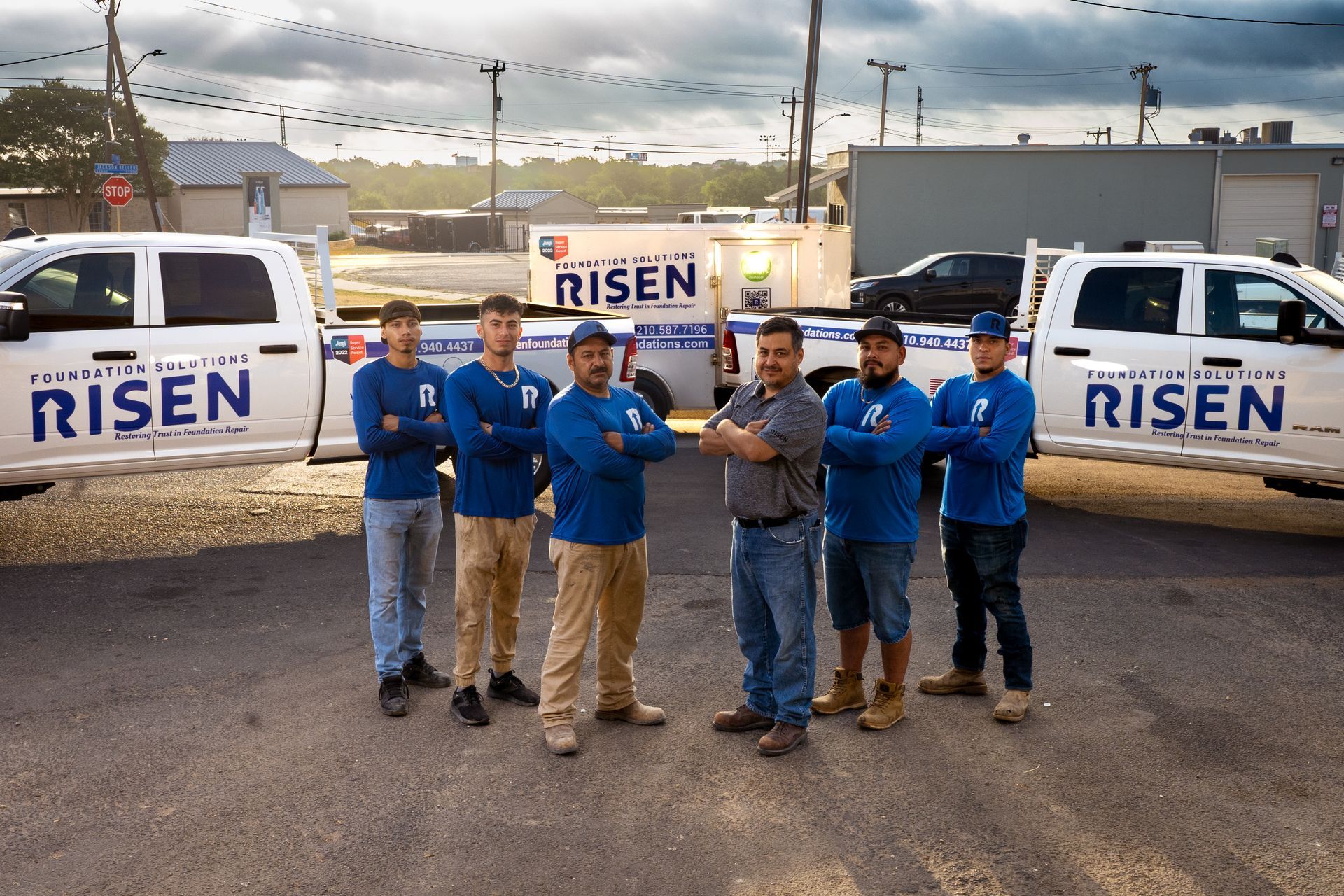 A group of men are posing for a picture in front of trucks that say risen.