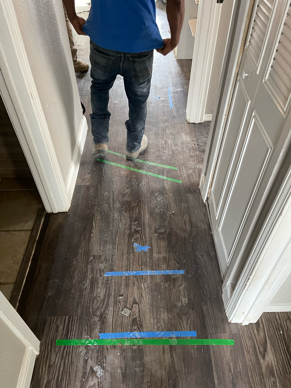 A person is walking down a hallway with tape on the floor.