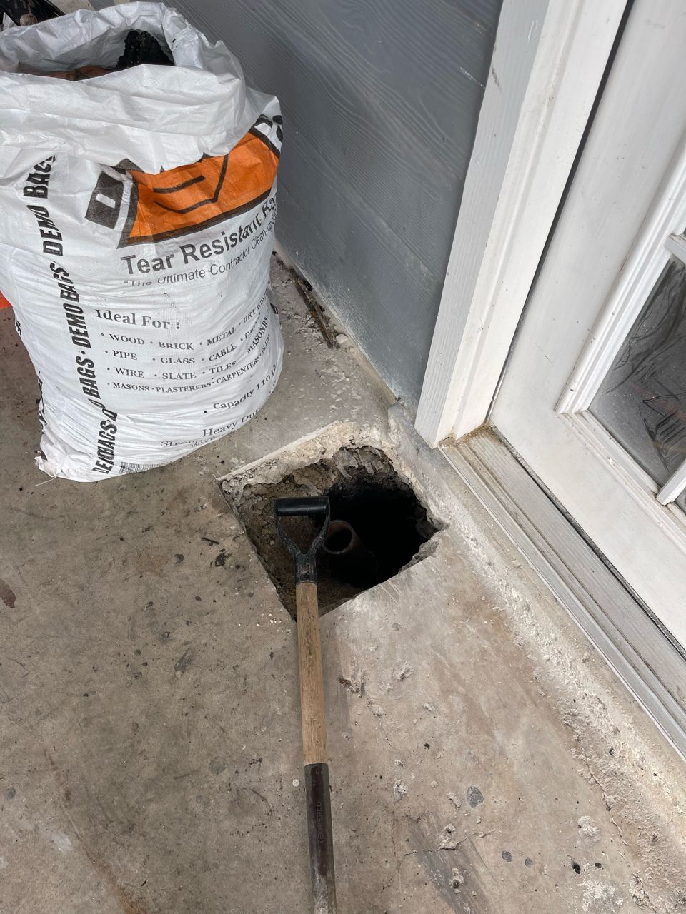 A bag of charcoal is sitting next to a hole in the ground.