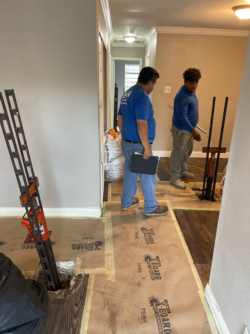 Two men are standing on a wooden floor in a room.