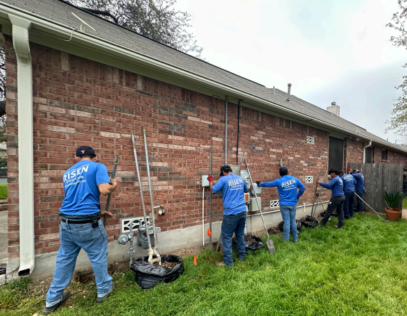 A group of men are working on the side of a brick house.