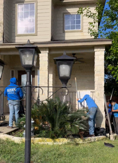 Foundation Repair with 27 Steel Piers in New Braunfels A group of men are working on the front of a house.