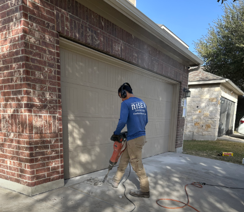 A man is working on a garage door with a hammer. A man is working on a garage door with a hammer.