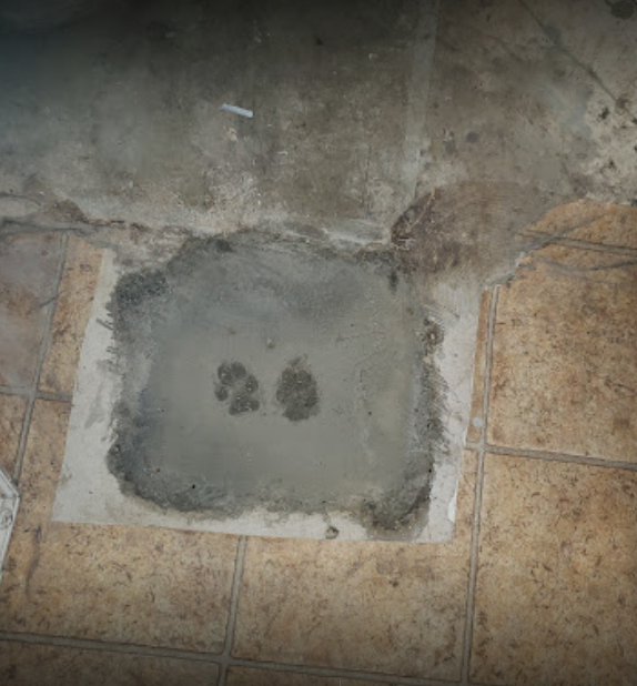 A piece of concrete is sitting on top of a tiled floor. House leveled with new piers