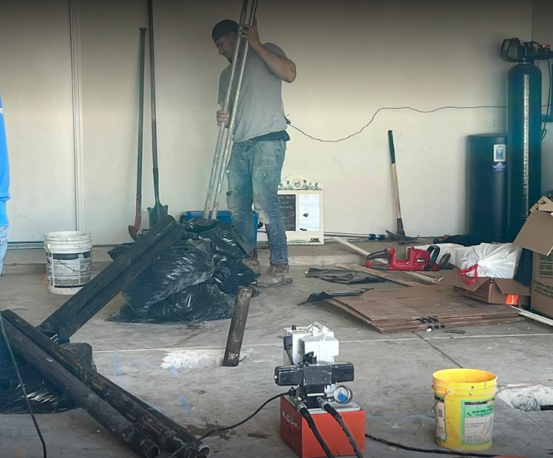 A man is standing in a garage holding a pole Foundation repairman working