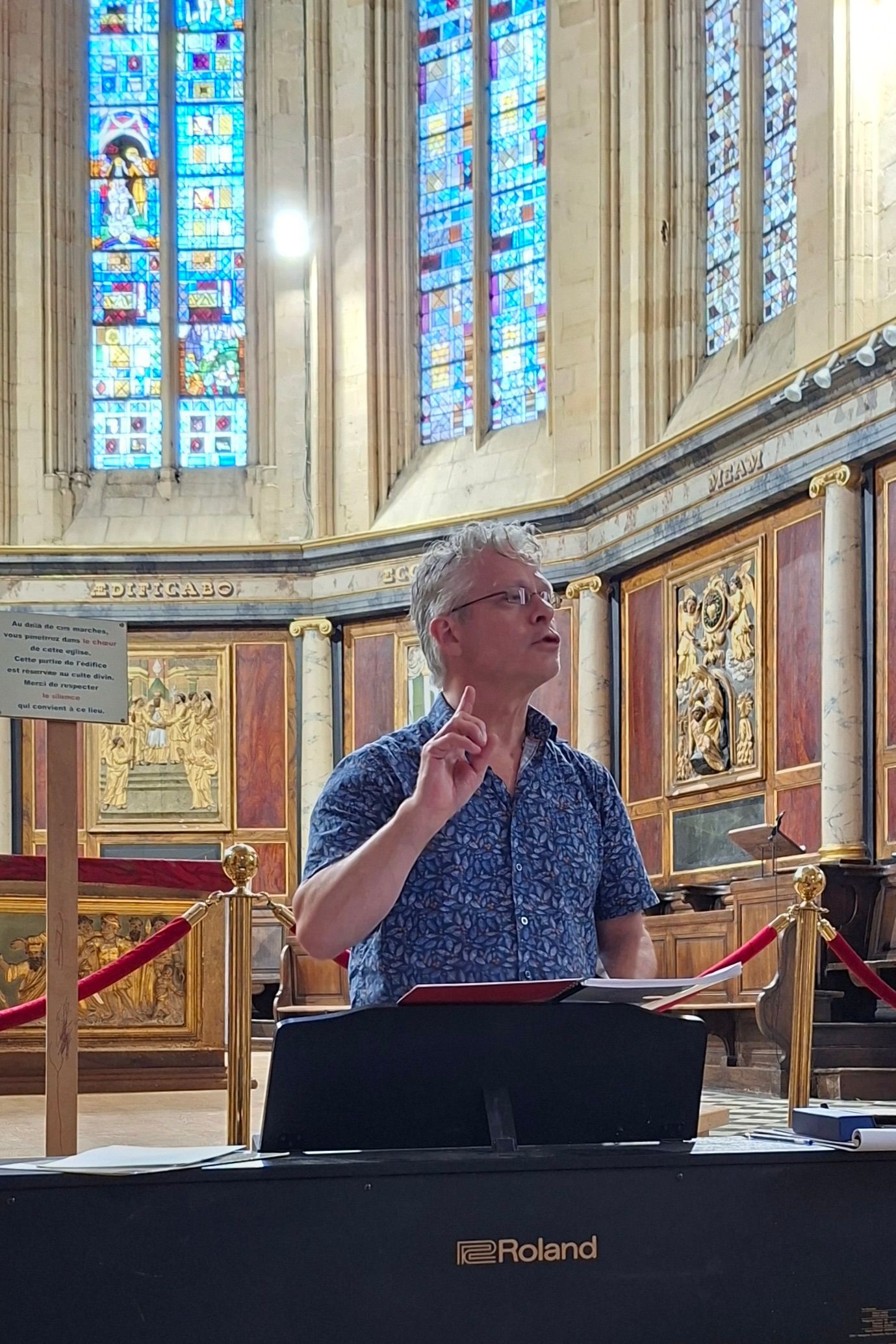 Een man spreekt vanaf een lessenaar in een kerk met glas-in-loodramen.