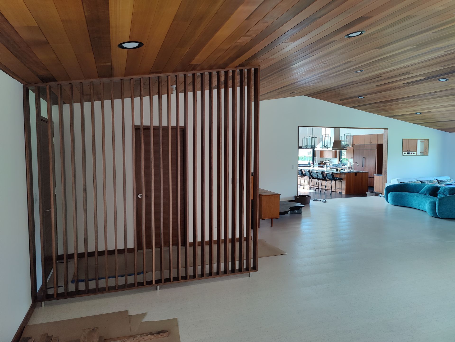 Kitchen cabinets, light blue with tan interiors, are being installed in a room