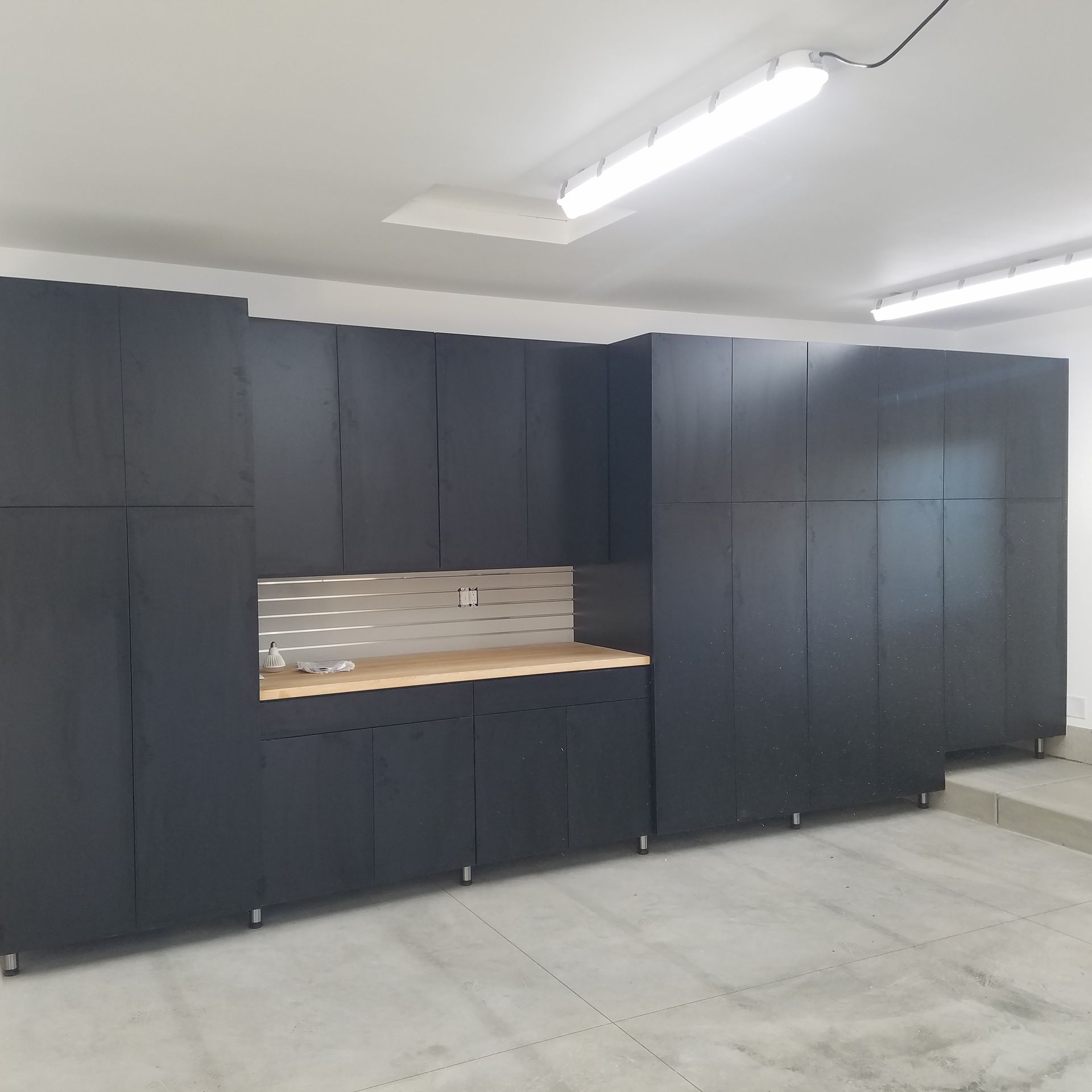 Garage interior with tools, workbench, cabinets, door, and vacuum cleaner Garage interior with tools, workbench, cabinets, door, and vacuum cleaner