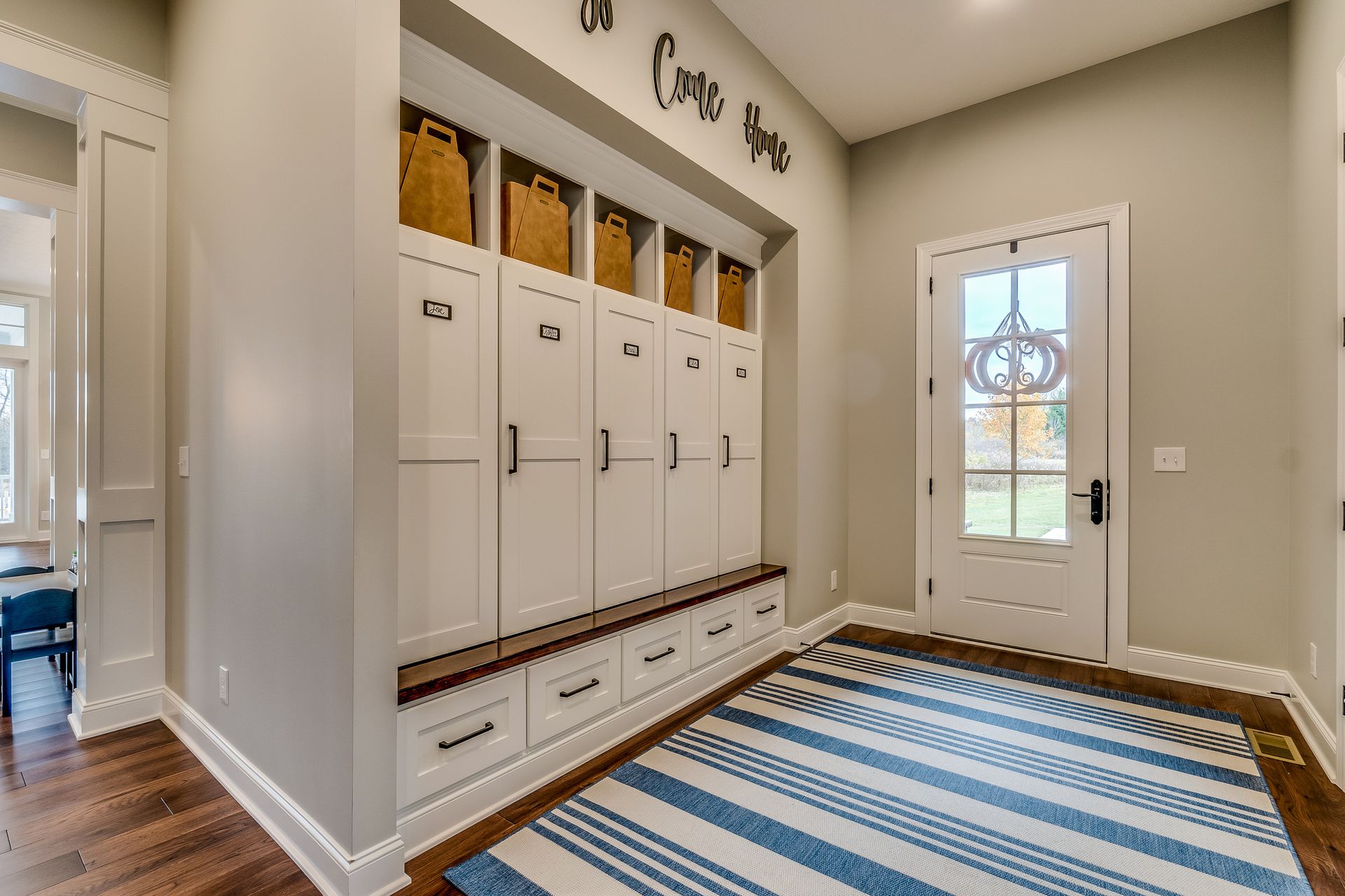 Entryway with white storage lockers and a wooden bench Entryway with white storage lockers and a wooden bench