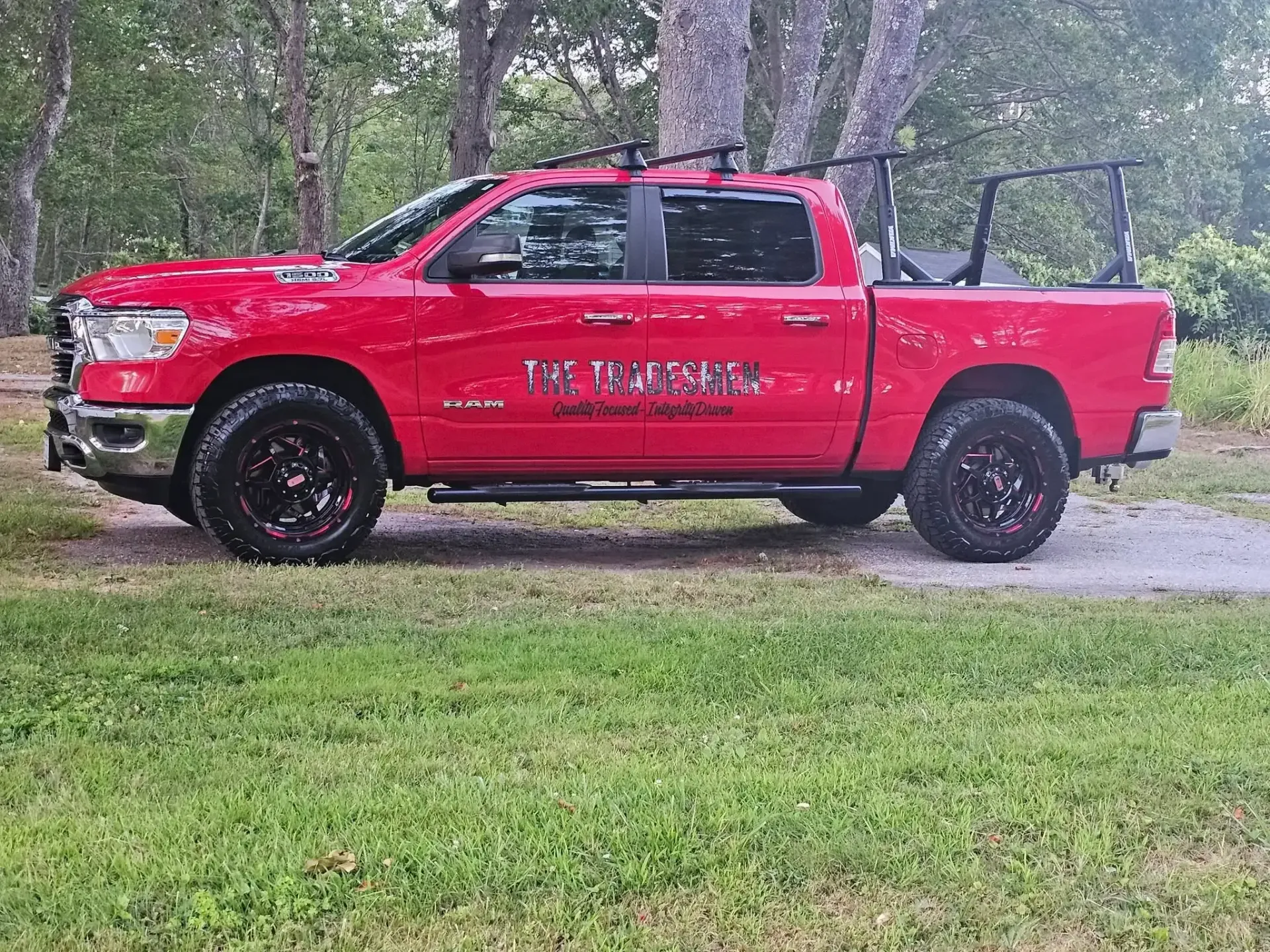 Red pickup truck with black wheels parked on grass.