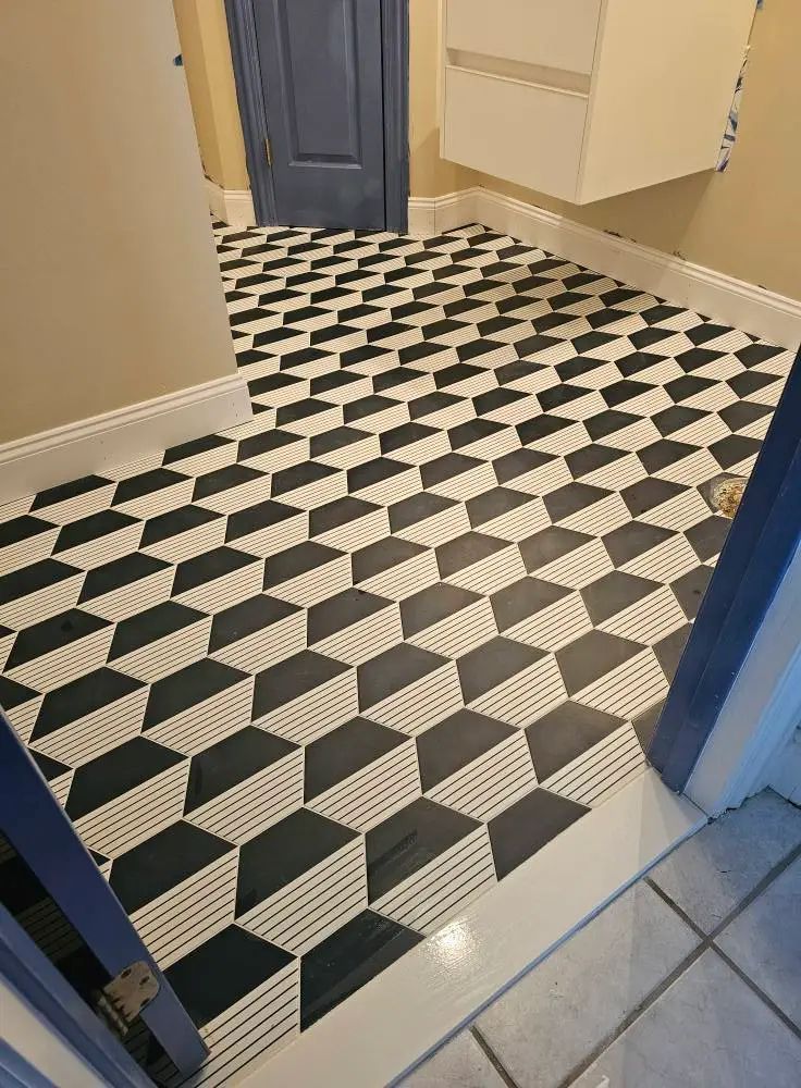 Black and white geometric tile floor in a room with blue door and white trim.