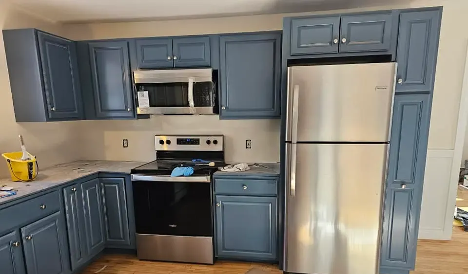 Blue kitchen cabinets with stainless steel appliances and white countertops.