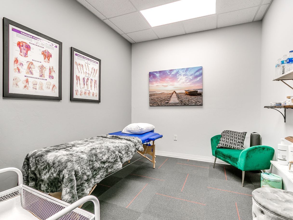 A room with a massage table and a green couch.