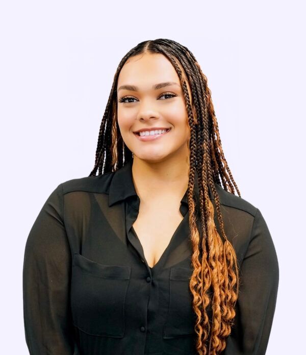 A woman with braids is wearing a black shirt and smiling.