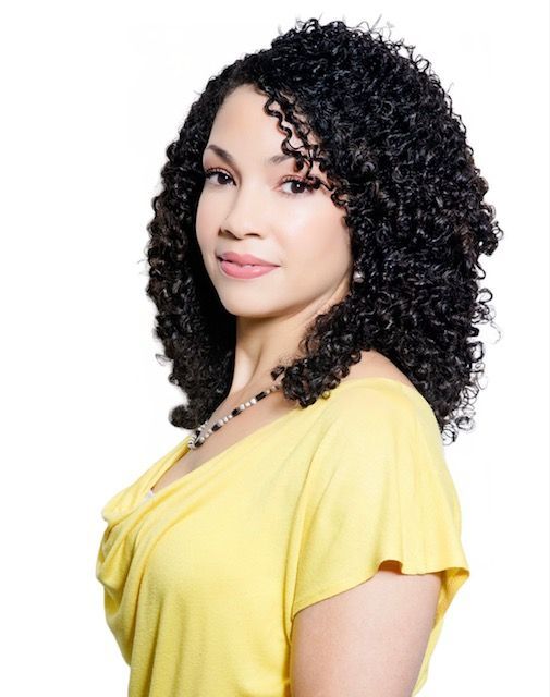A woman with curly hair is wearing a yellow shirt