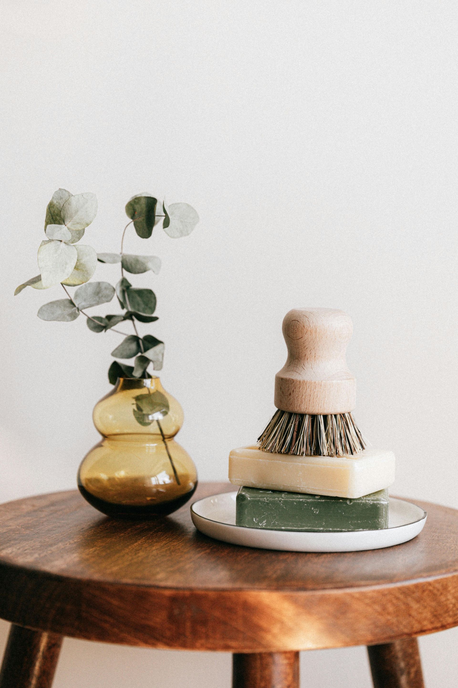 A wooden table with a vase and soap on it.
