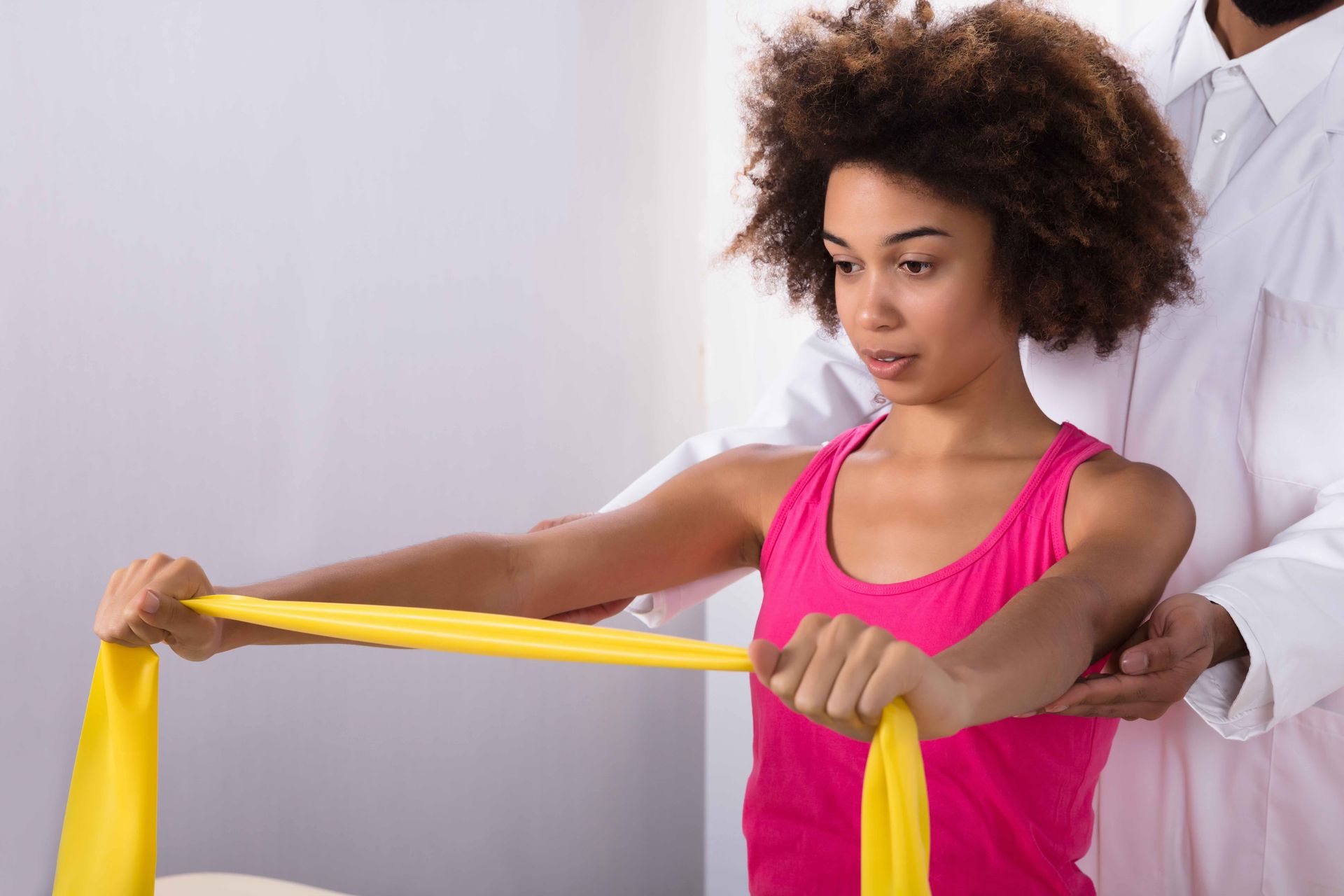 A woman is doing exercises with a yellow resistance band.