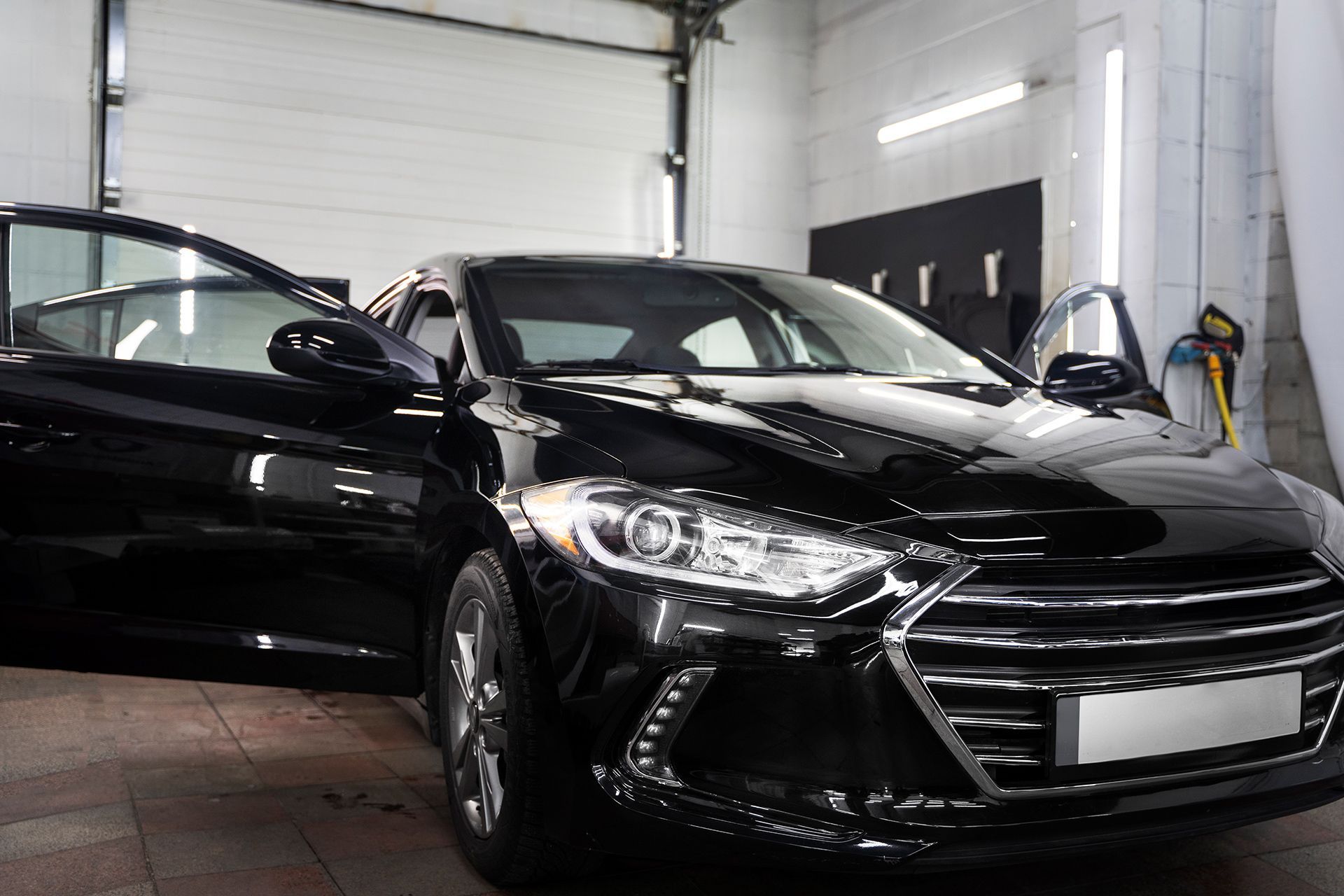 Black car in a garage with both front doors open