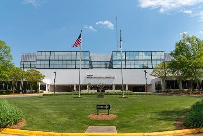 Exterior view of a modern hospital building with American flag on a sunny day.