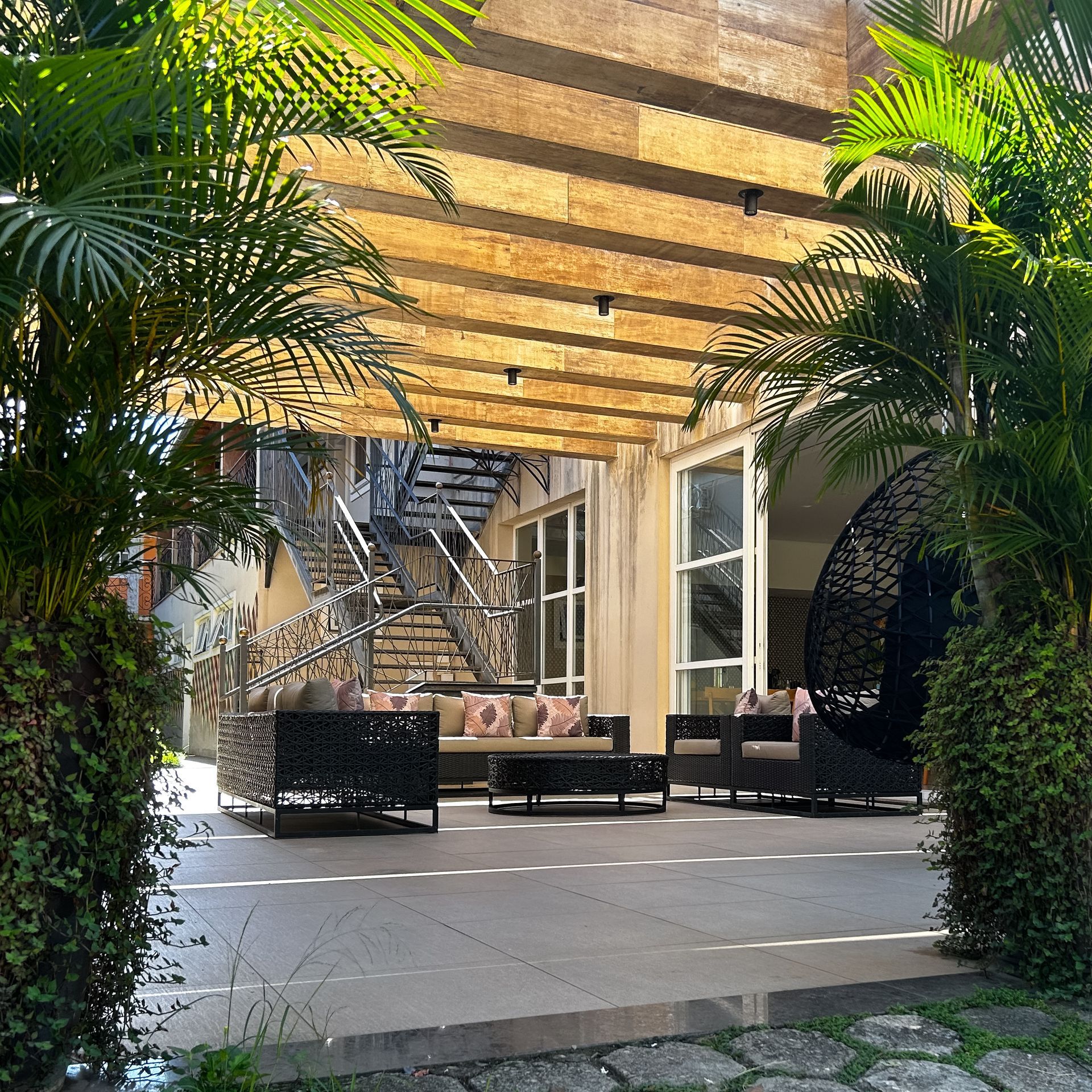 Um pátio com um sofá e cadeiras sob uma pérgola