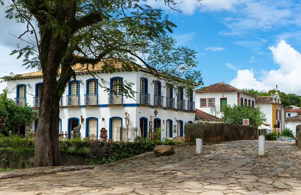 Um grande edifício branco com uma árvore na frente.