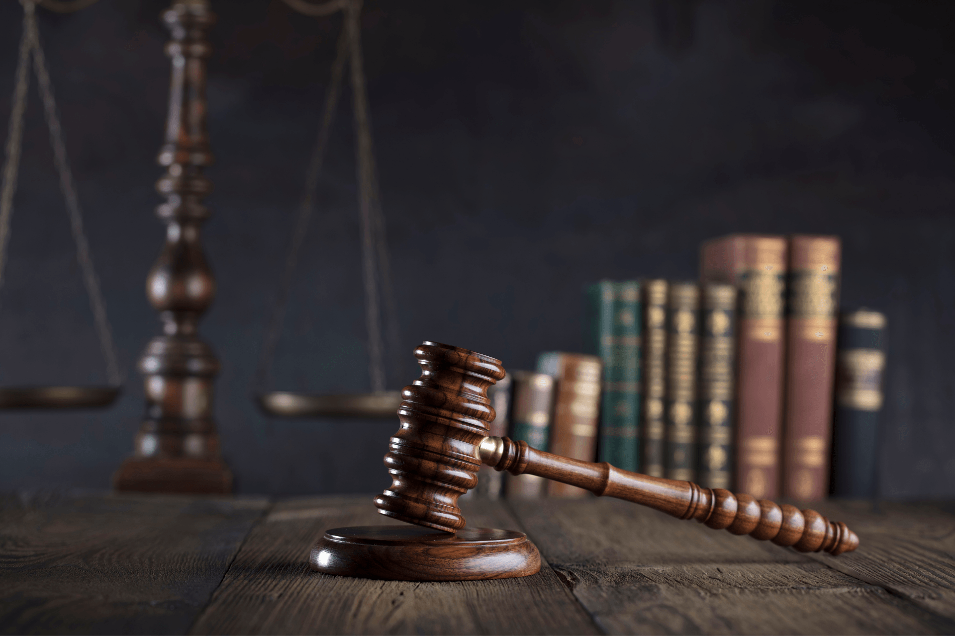 Judge's gavel on a wooden desk with law books and scales in the background