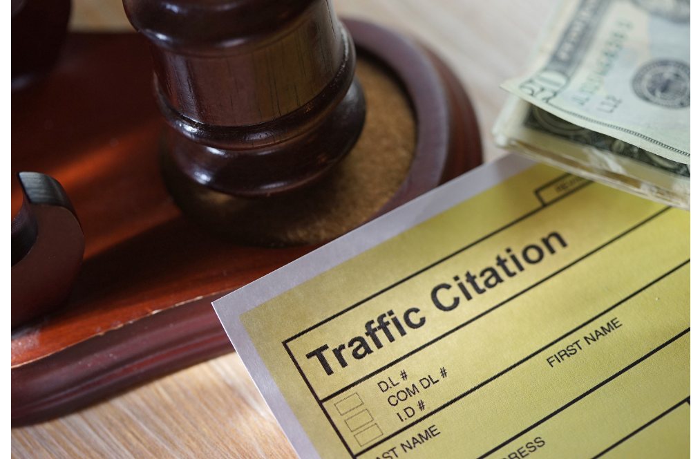 Traffic citation form beside a gavel and cash on a judge’s bench