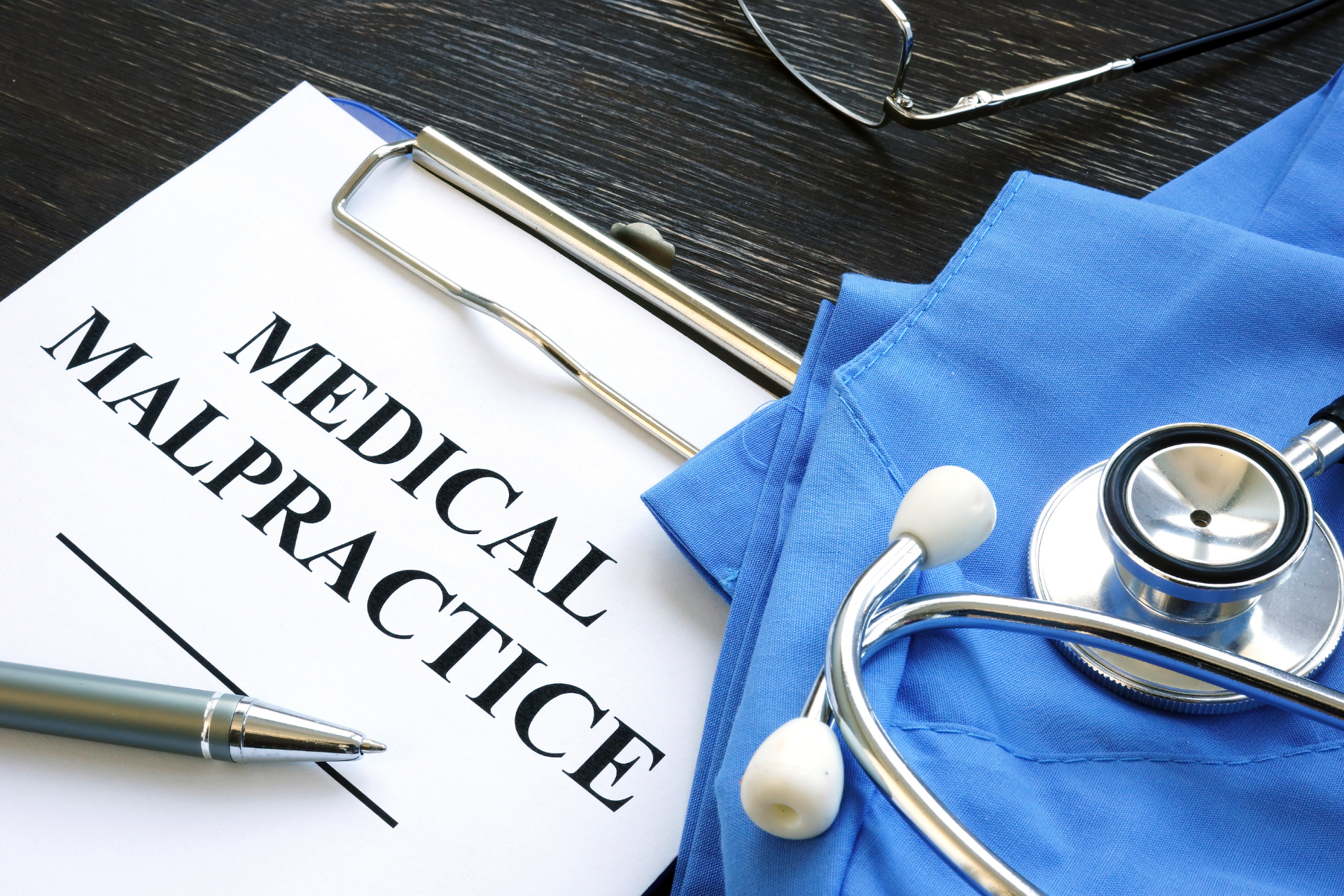 Medical malpractice document with stethoscope and blue scrubs on a desk