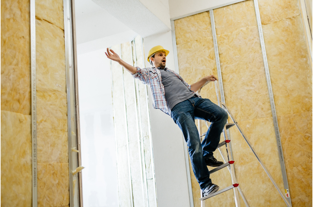 Worker on a ladder installing drywall in an unfinished room