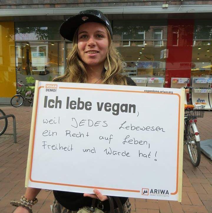 Frau hält ein Schild mit der Aufschrift: „Ich lebe vegan, weil jedes Lebewesen ein Recht auf Leben, Freiheit und Würde hat.“