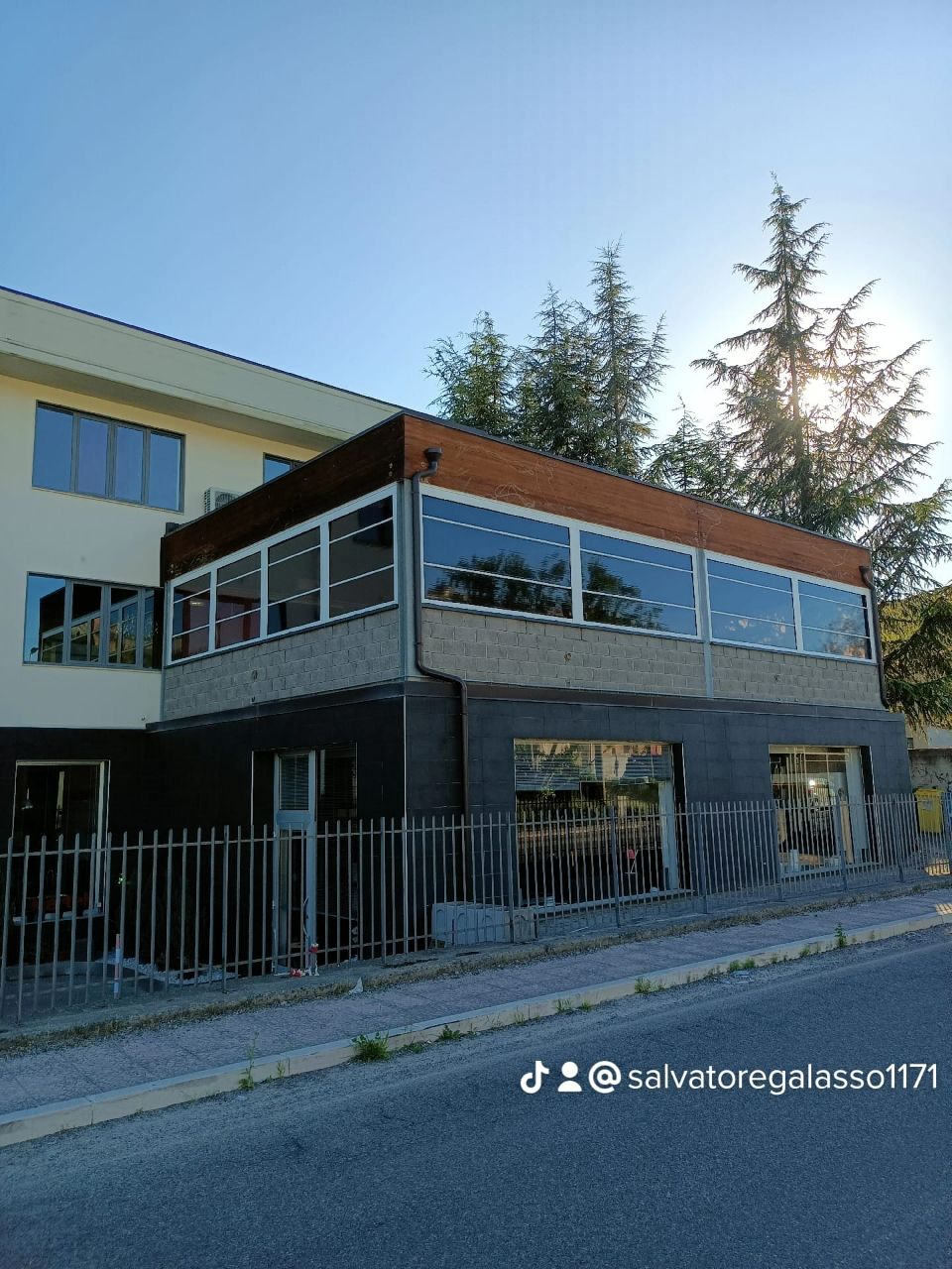 Moderno edificio a due piani con ampie finestre e facciata recintata, visto dalla strada.