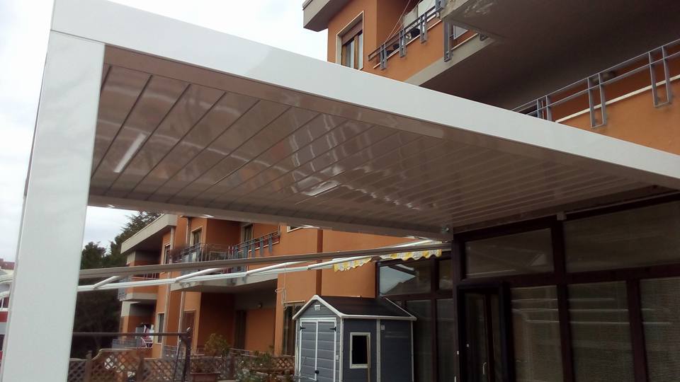 Passaggio coperto all'esterno di un condominio, con un piccolo capannone e balconi arancioni sullo sfondo.