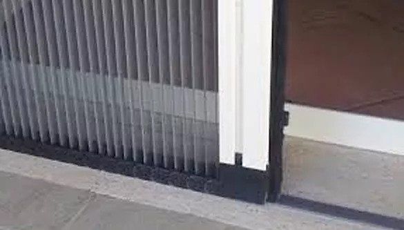 Tende verticali accanto a una porta aperta con cornice bianca e battiscopa scuro