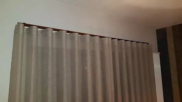 Tende grigio chiaro appese a un binario sul soffitto in una stanza con pareti beige.