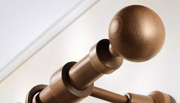 Primo piano di un terminale e degli anelli in bronzo per un'asta per tende su sfondo bianco.