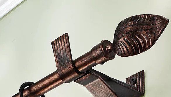 Asta per tende decorativa in bronzo scuro con pomello a forma di foglia e supporto, su una parete chiara.