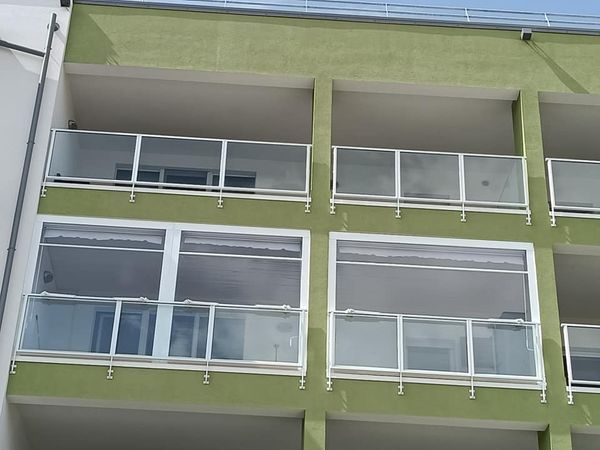 Esterno di un condominio verde con balconi bianchi e ampie finestre.